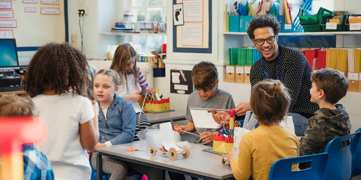 A teacher and students in the classroom doing a project.